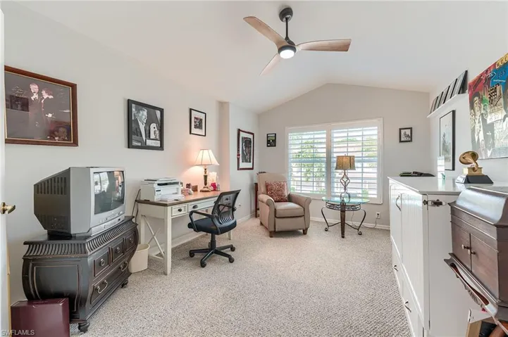 Office space featuring carpet floors, baseboards, lofted ceiling, and ceiling fan