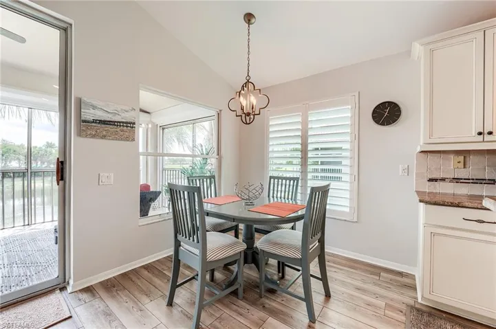 Dining area featuring lofted ceiling, light wood-style flooring, a healthy amount of sunlight, and an inviting chandelier