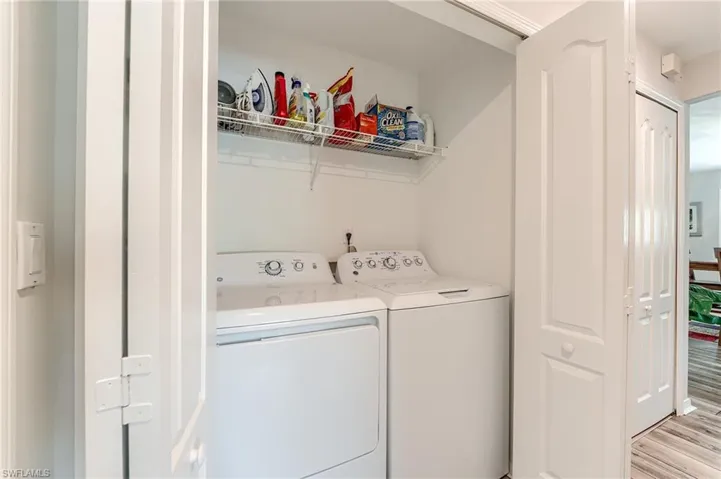Clothes washing area featuring washing machine and dryer, laundry area, and light wood-type flooring