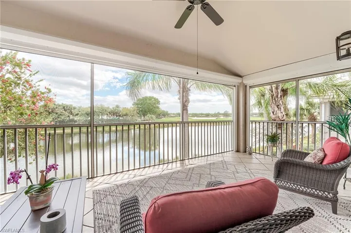 Sunroom / solarium featuring tile patterned floors, a water view, lofted ceiling, and ceiling fan