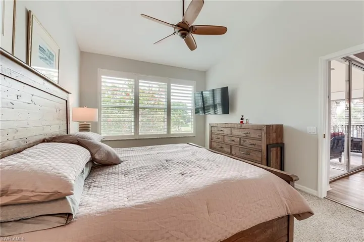 Bedroom featuring baseboards, access to outside, a ceiling fan, vaulted ceiling, and light colored carpet