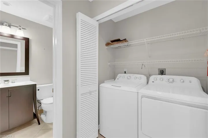 Laundry area with separate washer and dryer and light tile