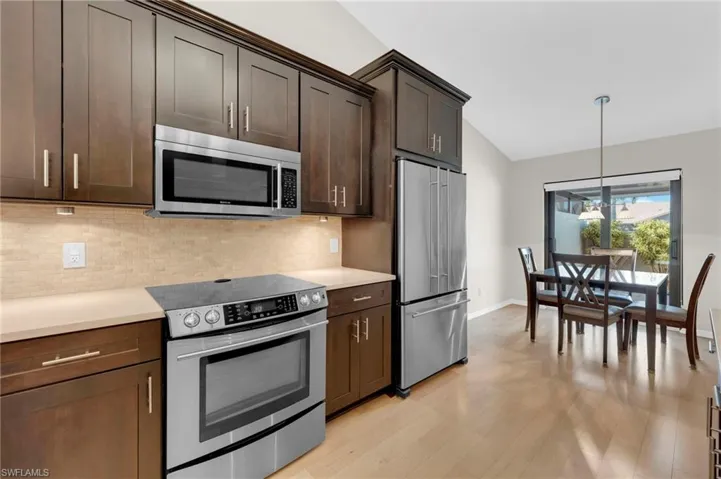 Kitchen featuring a chandelier, hanging light fixtures, stainless steel appliances, light wood-type flooring, and dark brown cabinets