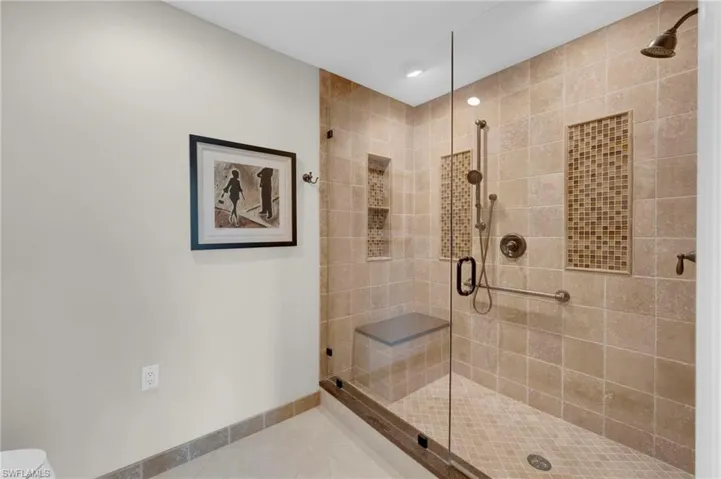 Primary bathroom shower with frameless glass shower doors and accent tiles