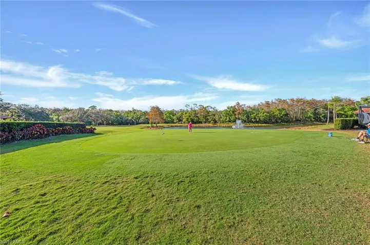 View of green lawn featuring view of scattered trees, view of golf course, and a water view
