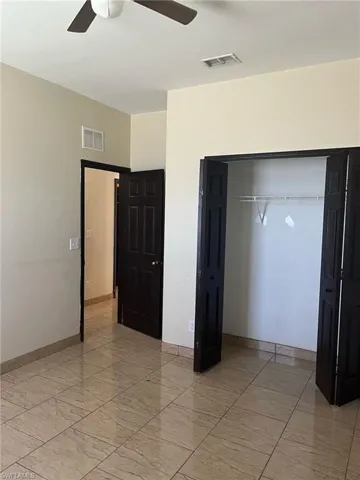 Unfurnished bedroom featuring a closet, ceiling fan, light marble finish floors, and baseboards