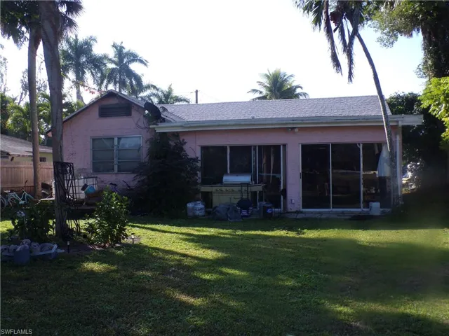 Rear view of property featuring a yard, a sunroom, and roof with shingles