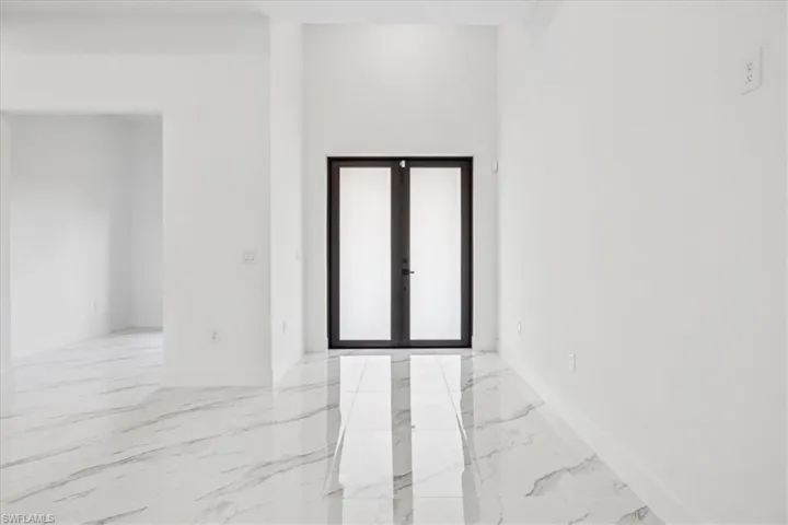 Empty room with light marble finish flooring and french doors