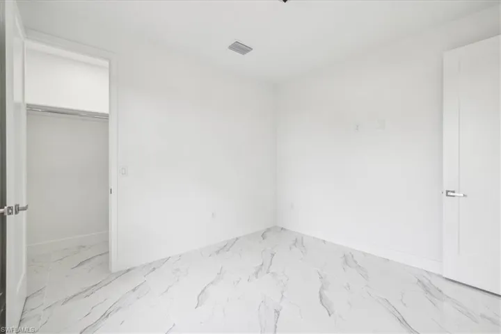 Unfurnished bedroom with light marble finish flooring and a closet