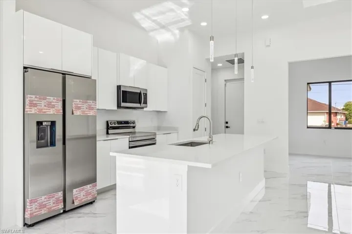Kitchen with light marble finish flooring, stainless steel appliances, white cabinets, modern cabinets, and light countertops