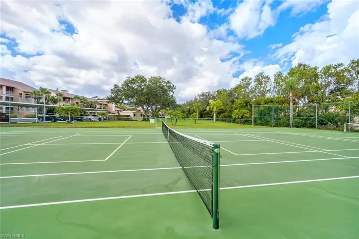 View of tennis court featuring basketball hoop