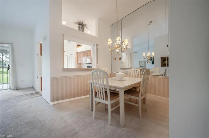 Carpeted dining area featuring a chandelier and high vaulted ceiling
