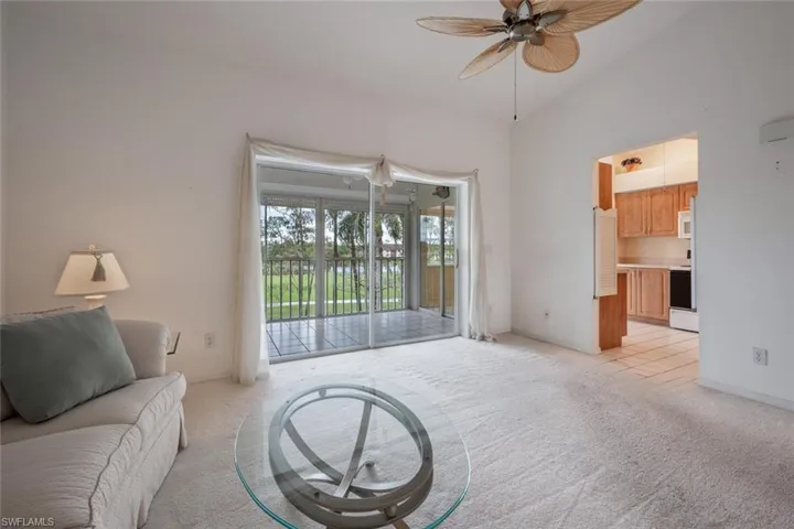 Carpeted living room featuring ceiling fan and vaulted ceiling