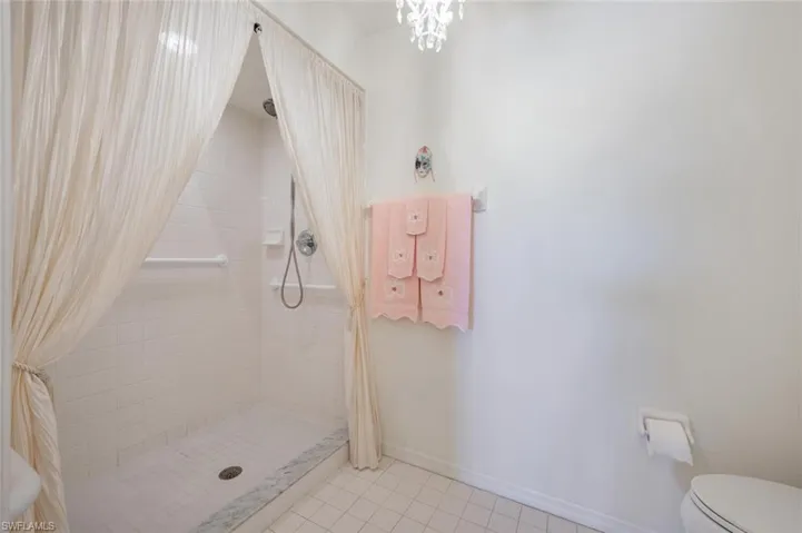 Bathroom featuring a shower with shower curtain, tile patterned flooring, and toilet