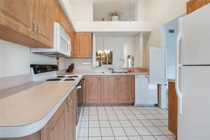 Kitchen featuring light tile patterned floors, white appliances, decorative light fixtures, and sink
