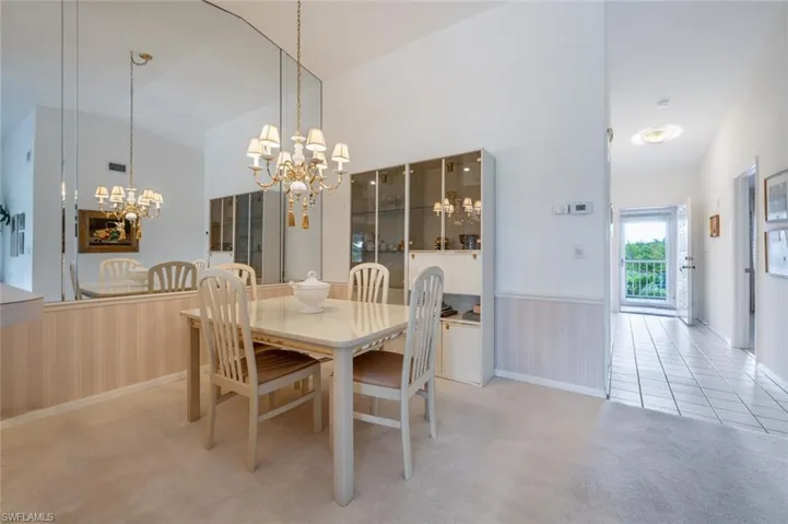 Carpeted dining room featuring high vaulted ceiling and a notable chandelier