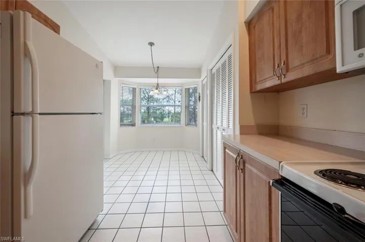 Kitchen with light tile patterned floors, hanging light fixtures, white appliances, and an inviting chandelier