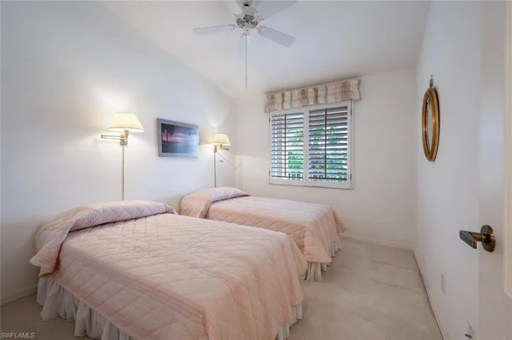 Bedroom with ceiling fan, light carpet, and vaulted ceiling