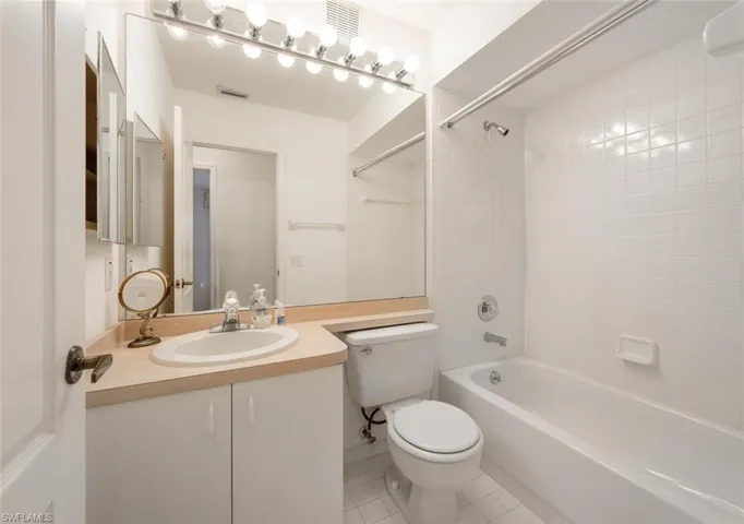 Full bathroom with tile patterned flooring, tiled shower / bath combo, toilet, and vanity