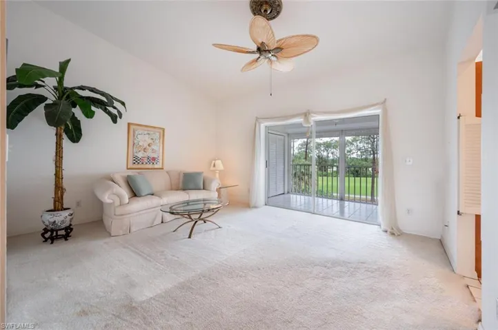 Carpeted living room with ceiling fan and lofted ceiling