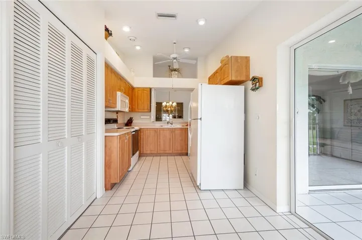 Kitchen with pendant lighting, white appliances, ceiling fan with notable chandelier, sink, and light tile patterned floors