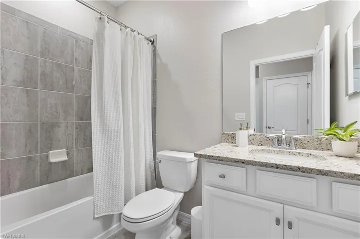 Full bathroom featuring shower / tub combo with curtain, vanity, and toilet