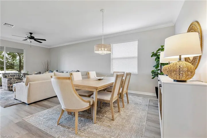 Dining space with ornamental molding, light wood-type flooring, and ceiling fan