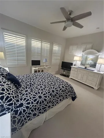 Bedroom featuring light carpet,  a ceiling fan and custom plantation shutters