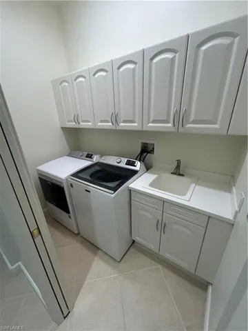 Laundry area featuring cabinet space, washing machine and dryer, and light tile patterned floors