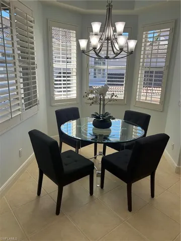 Dining room with a chandelier, light tile patterned flooring and custom plantation shutters