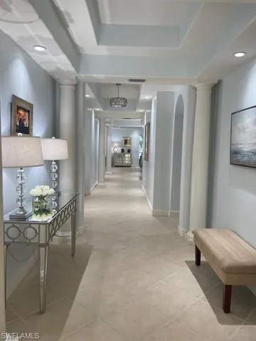 Hallway featuring decorative columns and light tile patterned floors
