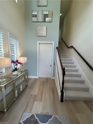 Stairway with wood finished floors and a high ceiling