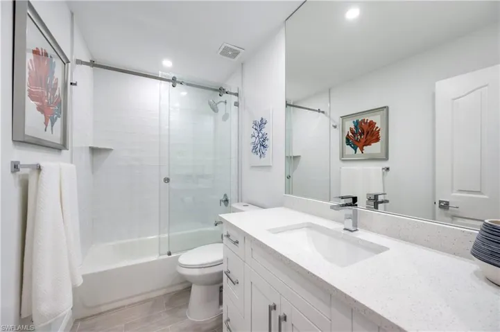 Bathroom featuring shower / bath combination with glass door, vanity, and wood finish floors