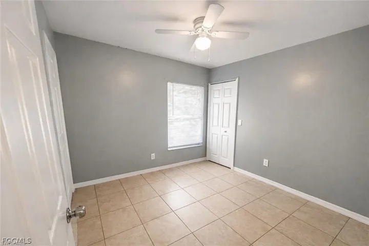Unfurnished bedroom featuring a ceiling fan, a closet, and light tile patterned flooring