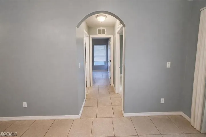 Hallway with arched walkways and light tile patterned floors