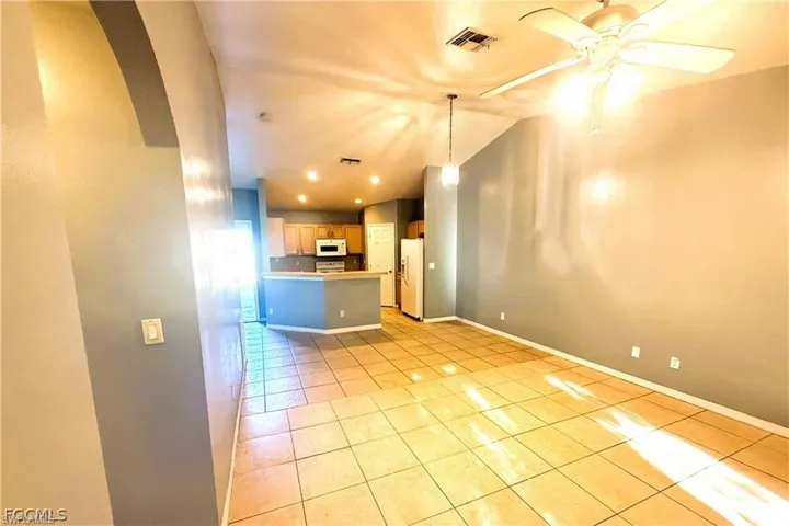 Unfurnished living room with vaulted ceiling, light tile patterned flooring, recessed lighting, ceiling fan, and arched walkways