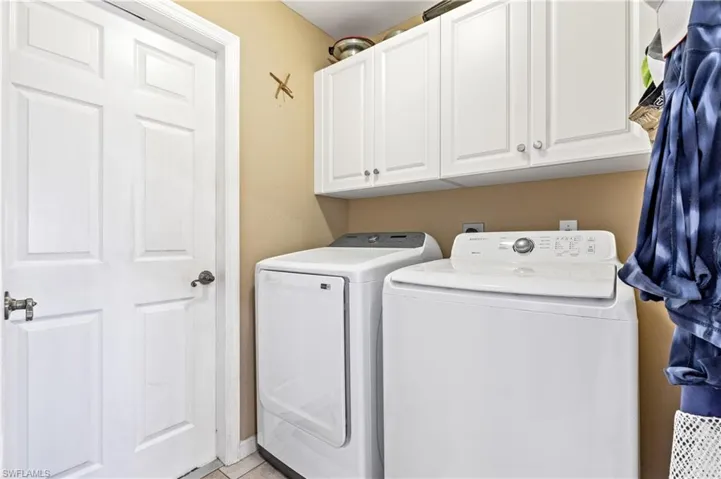 Laundry area with cabinet space, light tile patterned flooring, and separate washer and dryer