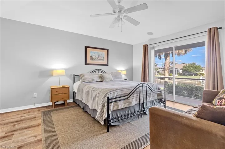 Bedroom featuring access to outside, wood finished floors, a ceiling fan, and a water view