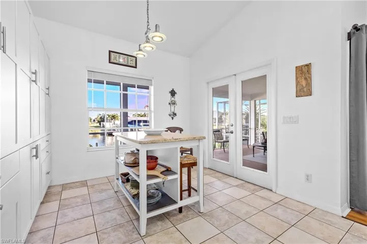 Dining room featuring french doors, lofted ceiling, light tile patterned floors, and a water view