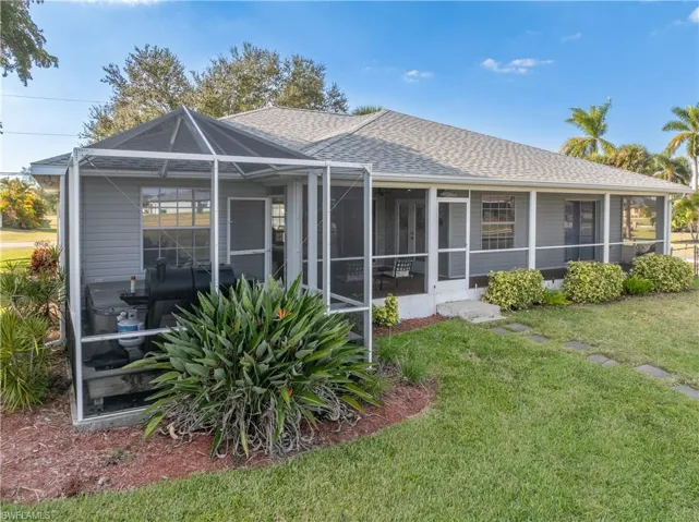 Back of house with a shingled roof, a lanai, a yard, and a sunroom