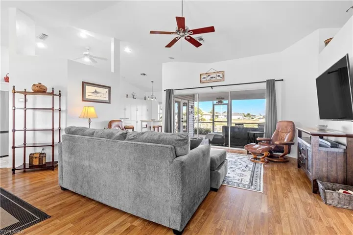 Living area with light wood-style floors, a ceiling fan, and high vaulted ceiling