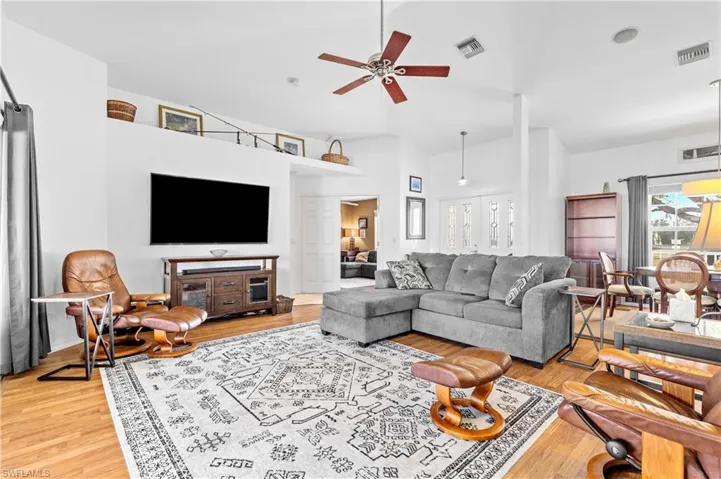 Living area featuring ceiling fan, light wood-style flooring, and high vaulted ceiling