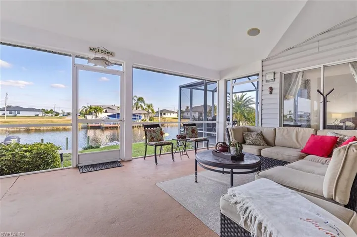 Sunroom featuring a residential view, a water view, vaulted ceiling, an outdoor living space, and concrete floors