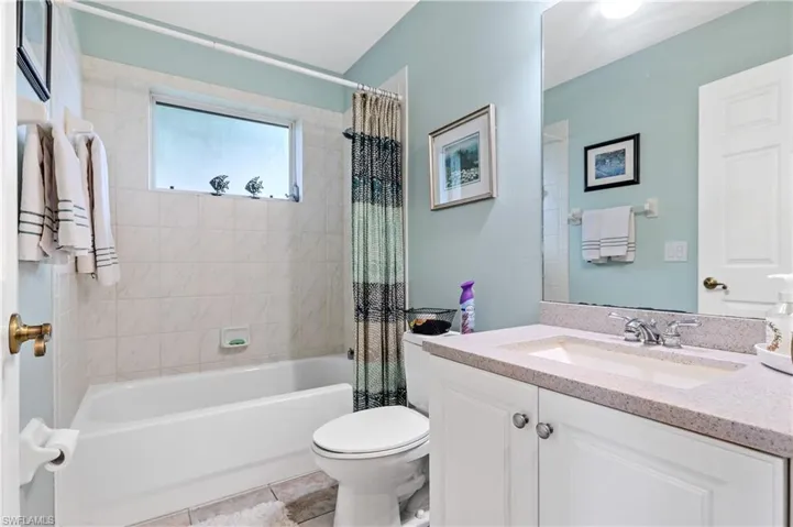 Bathroom featuring shower / bathtub combination with curtain, vanity, and light tile patterned floors