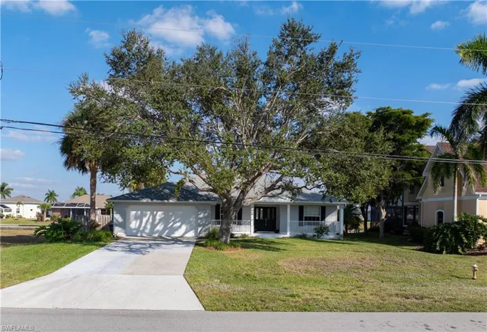 View of front of house featuring concrete driveway, a front lawn, an attached garage, and covered porch