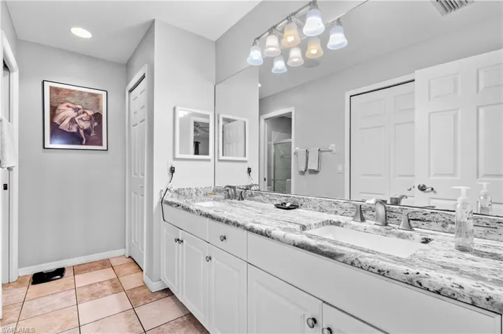 Bathroom featuring double vanity, a closet, light tile patterned floors, and a shower stall