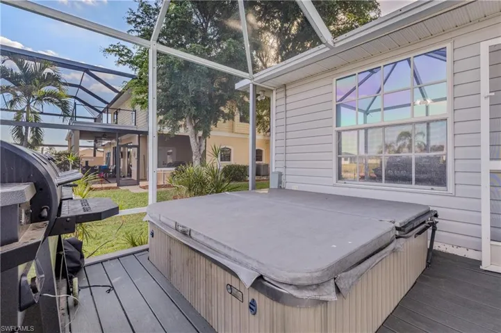 Wooden deck featuring glass enclosure, a hot tub, and a grill