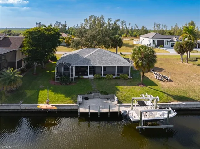Dock with a lanai, a yard, a water view, and a sunroom