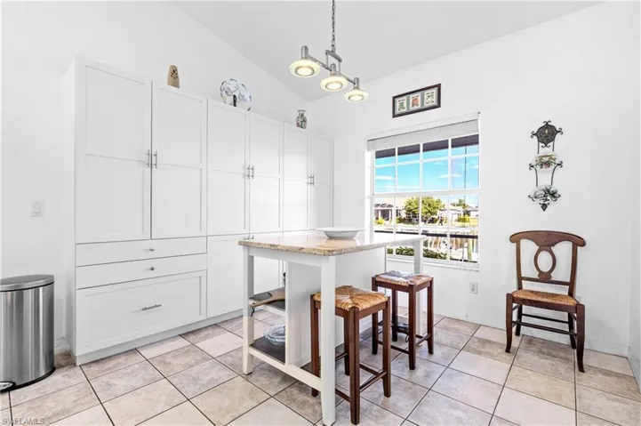 Dining space featuring light tile patterned floors and vaulted ceiling