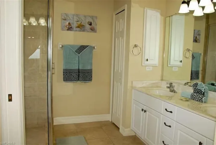Bathroom with a stall shower, tile patterned floors, a sink, a chandelier, and baseboards
